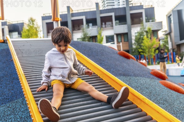 Preschool child having fun sliding down roller slide at playground in vancouver, british columbia,