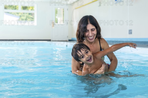 Mother and son smiling and playing together in a swimming pool, enjoying a fun filled leisure