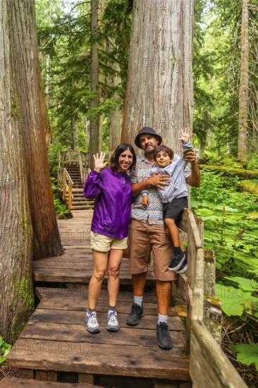 Tourists enjoying a summer hike waving at the camera on the giant cedars boardwalk trail in mount