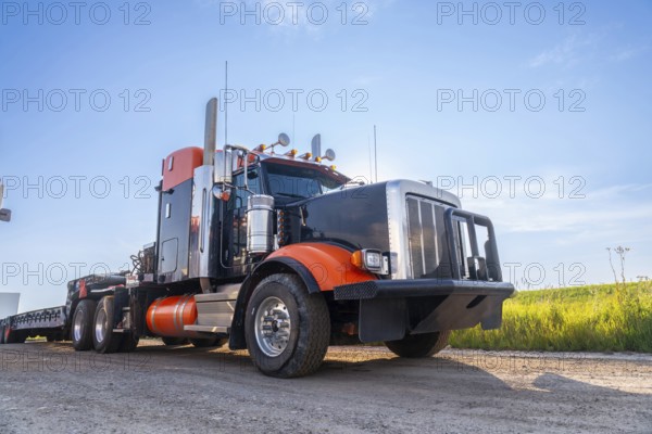 Powerful big rig semi truck with empty flatbed trailer parked on hemlock grove boardwalk in the