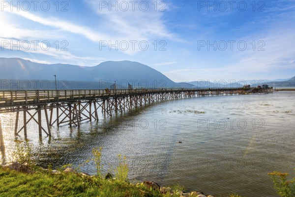 Long wooden pier stretching into the calm waters of shuswap lake in salmon arm, british columbia,