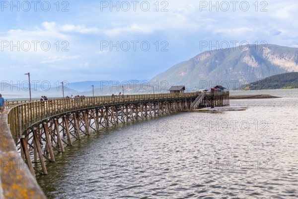 Tourists are enjoying a sunny day walking on the longest wooden wharf in north america, located in