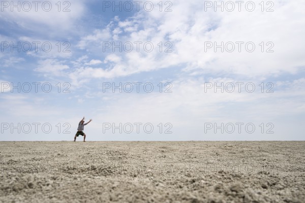 Symbolic picture, abstract, man raising his hands conjuring, on the Etosha pan, salt pan, Etosha