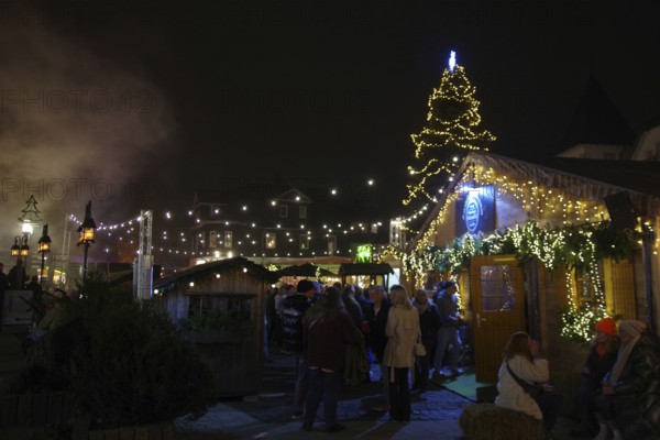 A lively Christmas market at night with illuminated wooden stalls and lots of visitors, Winterberg,