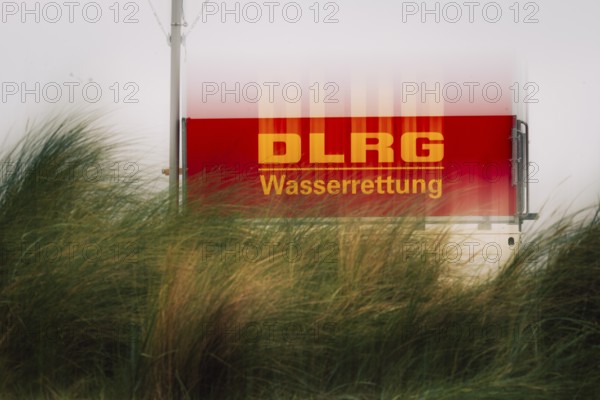 DLRG sign on the coast, red sign with the inscription DLRG Wasserrettung partly covered by high