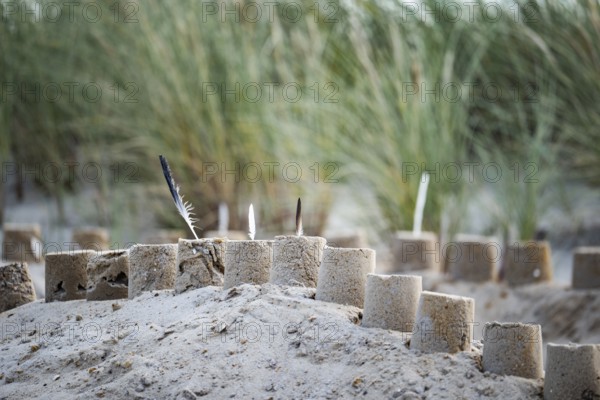 Sandcastle on the beach, detailed view of a sand castle with small towers and dug in the sand,
