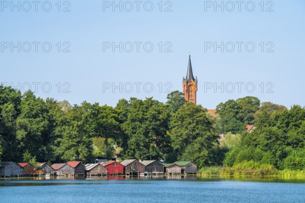 View across the Haussee to the town church and colorful boathouses on stilts, Feldberg, Feldberg