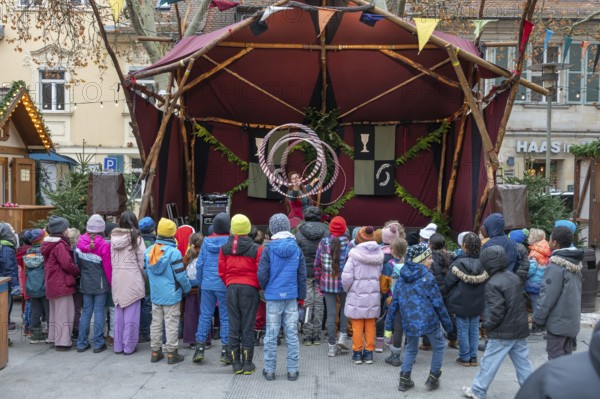 A group of children watches an acrobat on stage, Historischer Christmas market am Neustädter church