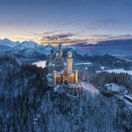 Snowy Neuschwanstein Castle surrounded by alpine mountains at dusk, Schwangau near Füssen,