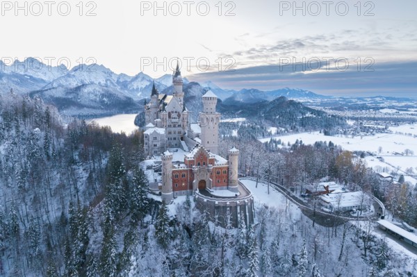 Snowy Neuschwanstein Castle at dusk, surrounded by mountains and soft winter light, Schwangau near
