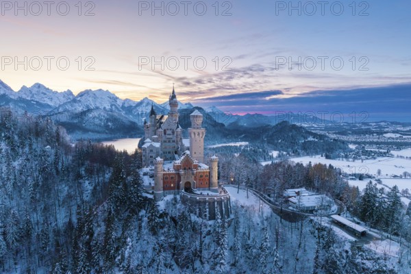Neuschwanstein Castle in winter at sunset with snow-covered mountains and peaceful atmosphere,