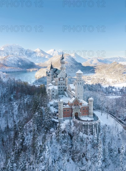 Neuschwanstein Castle in a wintry landscape with snow-covered mountains and blue sky, peaceful