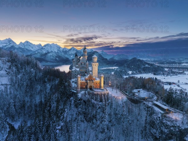 Picturesque Neuschwanstein Castle in winter at dusk with alpine panorama, Schwangau near Füssen,