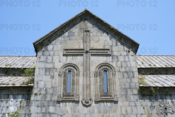 Historic church façade with stone cross and windows under a blue sky, Akhtala monastery, Akhtala