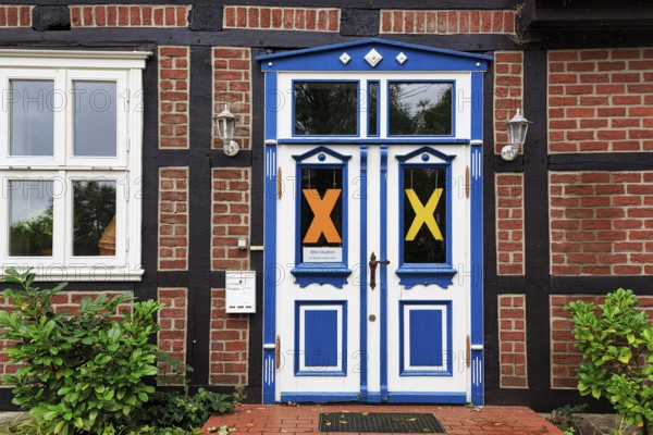 Characteristic half-timbered house, façade detail, blue white door, yellow X symbol, resistance