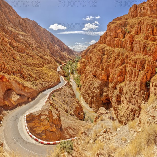 Serpentine road through steep, red rock walls under blue sky, Morocco, Dade Valley, panorama