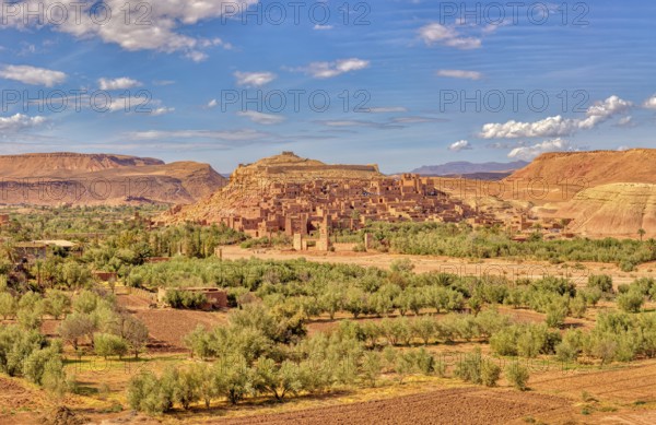 Historic clay buildings in an oasis surrounded by desert landscape, Morocco, Ait Ben Haddou,