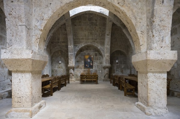 Stone vault with wooden furniture and paintings on the wall, sparse interior, refectory interior,