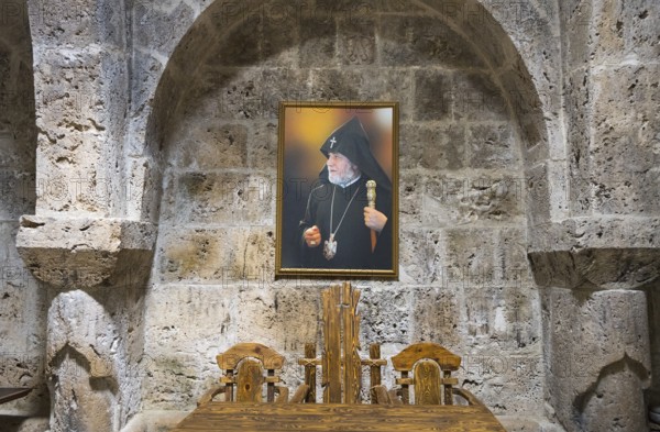Interior view with painting of a religious motif in front of a stone wall and wooden furniture,