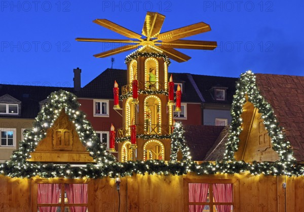 The Christmas market with the mulled wine pyramid in front of apartment buildings in the evening,