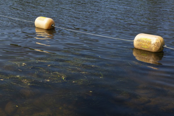 String of yellow cautionary navigation buoys on river water surface serving to warn, signal or