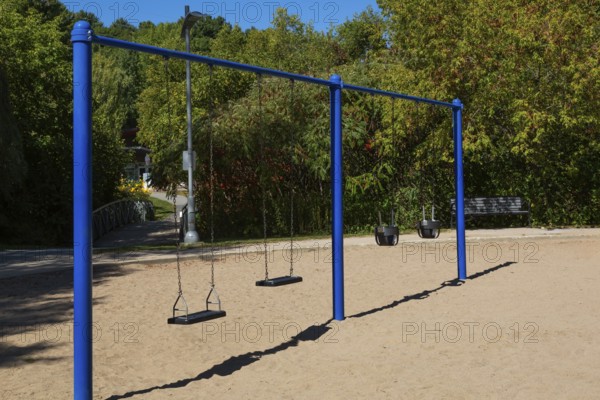 Swings installed in sandy ground in kids playground in city park in late summer, Parc du