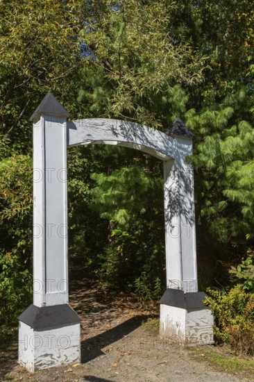 White painted wooden portal gate at start of hiking trail in public nature park in late summer,