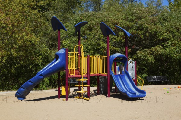 Kids playground equipment with slides, climbers and monkey bars installed in sandy ground in city