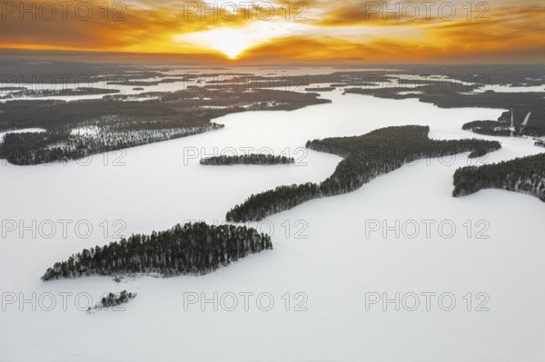 Aerial view over forest and snow covered frozen Lahnaselkä lake in Kuusamo in winter, Koillismaa,