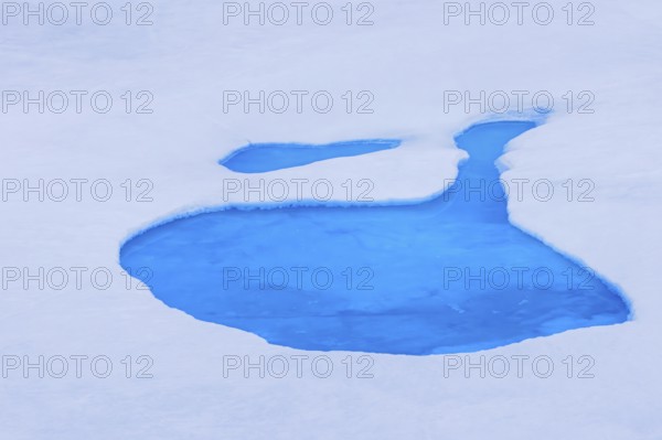 Aerial view over vivid blue water of meltpond / melt pond / meltwater pool on sea ice in the Arctic