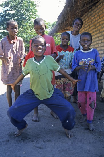 Local children dance happily to music in a village near Kande, Lake Malawi, Malawi, Africa, July