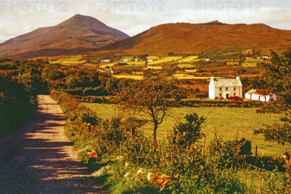 Farmland and rural landscape country road leading towards Derryveagh Mountains mountain range,