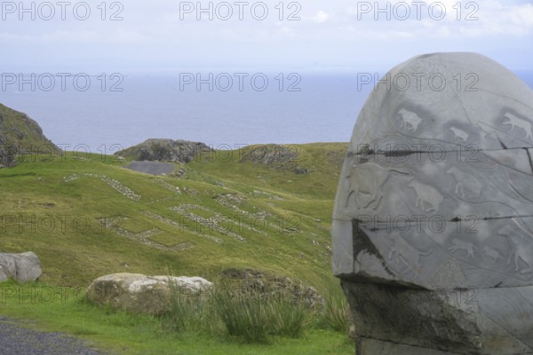 Stone monument with animal representations in the background Eire sign, on the way to the Slieve