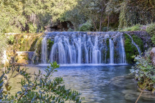 Fascinating waterfall flowing over green moss rocks into a natural basin, El Kelaa wild stream in