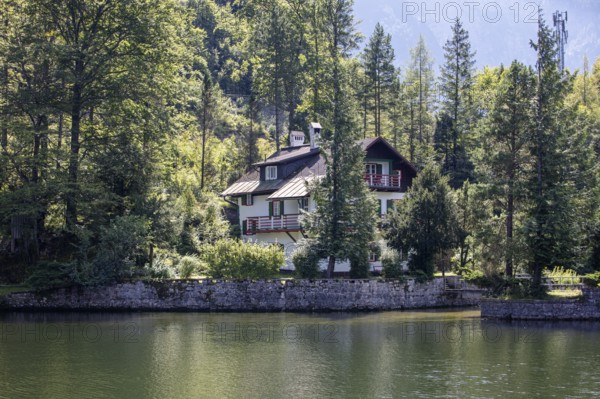 A, Hallstatt, A cozy house tucked away on the edge of a quiet lake surrounded by thick forest,