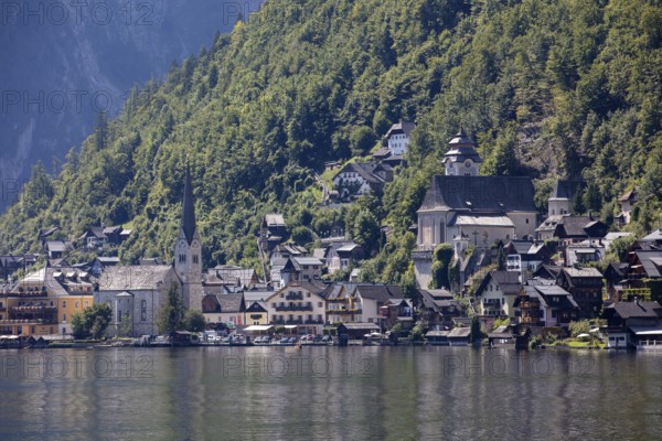 A, Hallstatt, A picturesque mountain village with lakeside churches in front of a steep forest