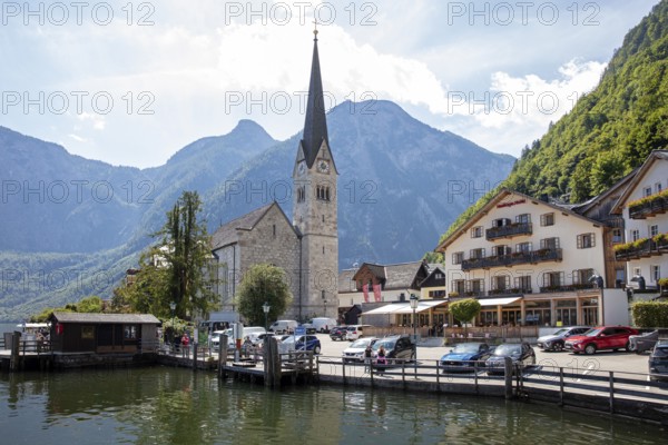 A, Hallstatt, church next to a lake in front of impressive mountains and clouds, quiet scenery,