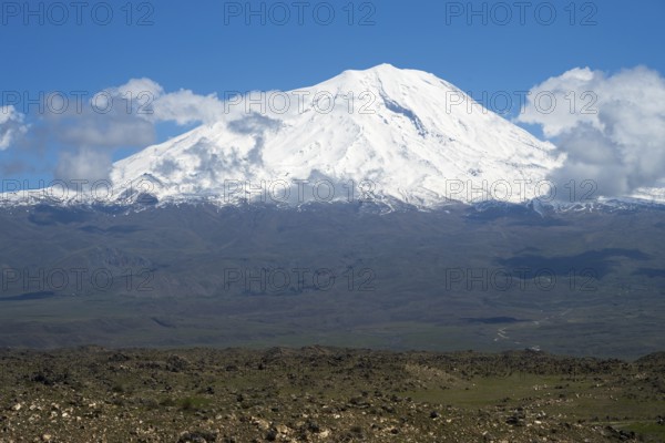 Impressive snow-covered mountain surrounded by clouds in a wide landscape, landscape near