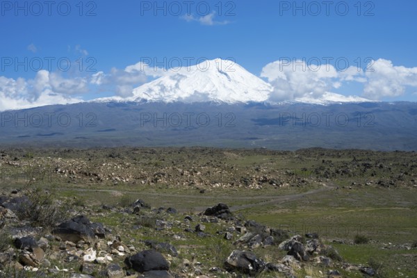 Peaceful landscape with snow-covered mountain and rocky plains under blue sky, landscape near
