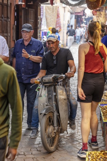 Lively Moroccan street with passers-by, motorcyclists and a historic atmosphere