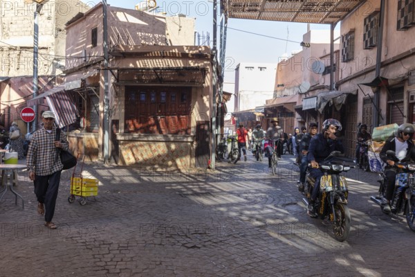 Busy street with motorcyclists and pedestrians in a sunny neighborhood