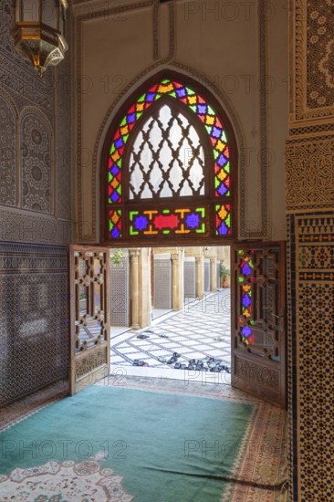 A sumptuous interior with a colorful stained glass window that throws light into the room in
