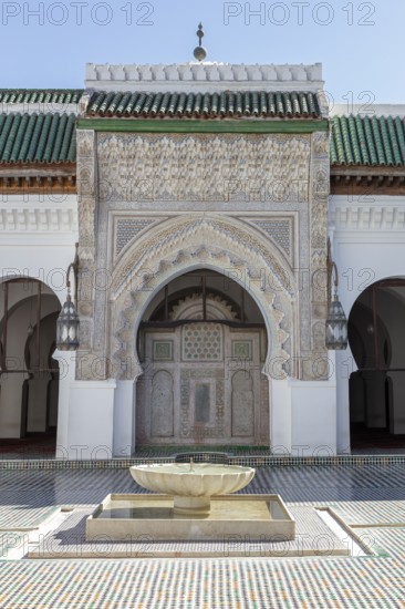 A richly decorated Islamic building with a central well, surrounded by mosaics and Islamic