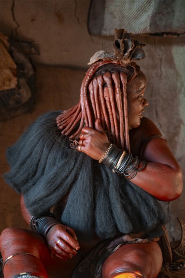 Elderly Himba woman showing her hair and jewelry, in a hut, traditional Himba village, Kaokoveld,