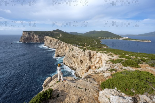 Tourist enjoying the view of steep cliffs by the sea, coastal landscape, cliffs on the Capo Caccia
