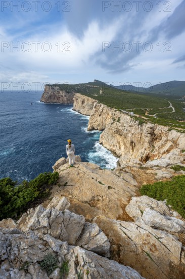 Tourist enjoying the view of steep cliffs by the sea, coastal landscape, cliffs on the Capo Caccia