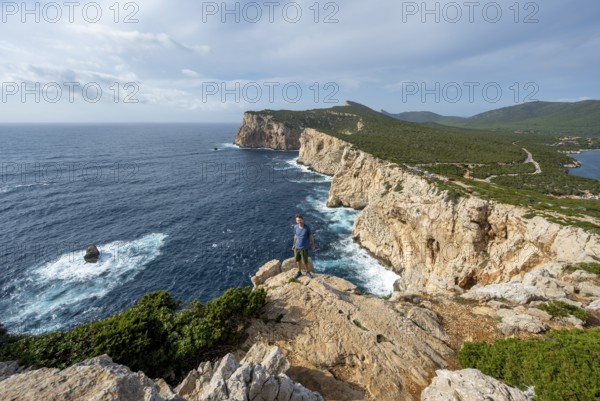 Tourist enjoying the view of steep cliffs by the sea, coastal landscape, cliffs on the Capo Caccia