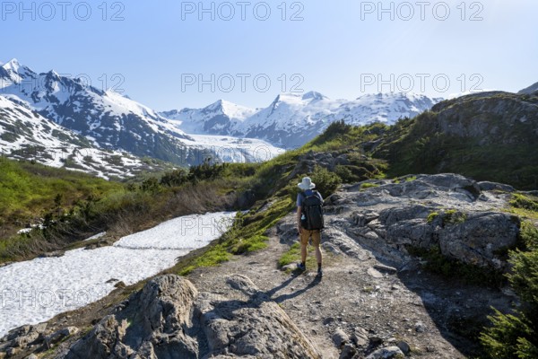 Hikers on the Portage Pass Trail, snow-covered mountains and Portage Glacier glaciers, near