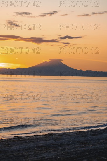 View of Cook Inlet on white mountain peaks of Mount Redoubt at sunset, picturesque golden light of