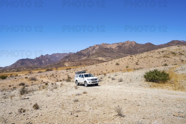 Toyota Hilux off-road vehicle on a sandy track, desert landscape with Brandberg, Erongo,